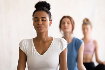 Women of diverse backgrounds meditate together.
