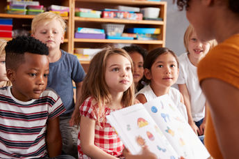 A teacher reads a story to young students.