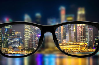 Looking through the lenses of glasses and seeing a bright cityscape at night.