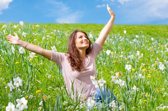 Happy woman sitting in a field of daffodils.