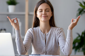 A woman takes a break from work to mediate and regain energy.