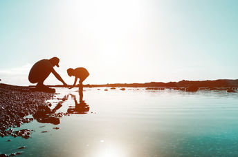 Silhouette of father and son playing on the beach at sunset