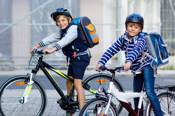 Two boys riding bicycles to school.