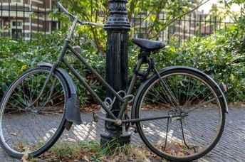 A bicycle chained to a post.