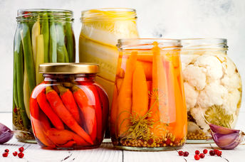 An appetizing selection of marinated pickled vegetables in glass jars.