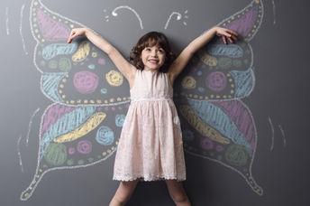 Little girl with a chalked butterfly behind her, a symbol of positive change and creativity.