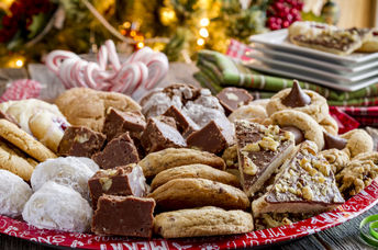A plate of holiday treats in front of a Christmas tree.