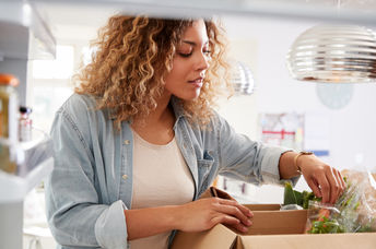 Woman carefully unpacks home food delivery