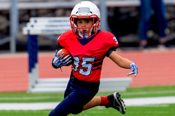 Young athletic boy playing in a youth tackle football game