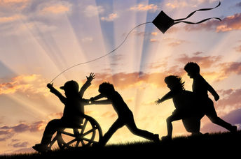 Happy boy in wheelchair playing with children and kite.