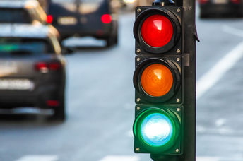 A traffic light, pedestrian crossing, and cars at a busy intersection.