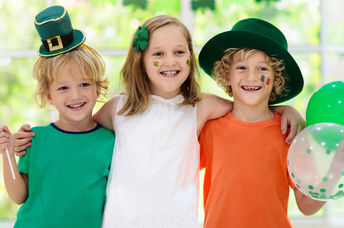 Children celebrate St. Patrick's Day by wearing a leprechaun hat and waving an Irish flag.