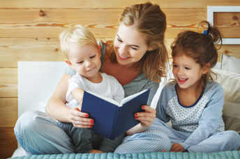 Mother reading a book to her children.