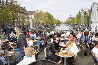 People enjoy a gezellig life sitting in an outdoor cafe Amsterdam.