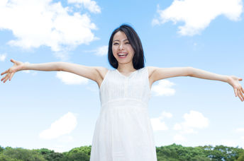 A woman happily embraces a sunny summer’s day.