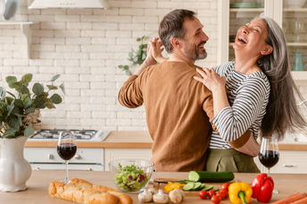 Happy couple dancing together in the kitchen while cooking.