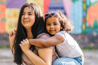 A mother carries her daughter.