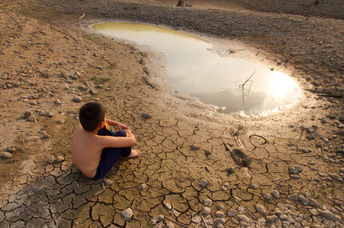 A child sitting near by a water source.