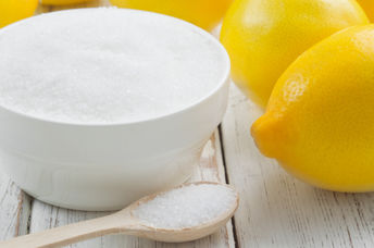 A bowl of citric acid beside lemons.