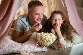Father and daughter enjoying a dog-themed movie together.