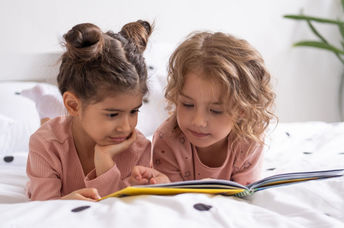 Two sisters reading a book before bedtime.