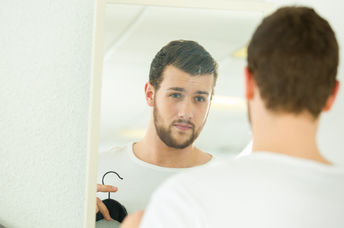 A man getting ready in front of the mirror. 