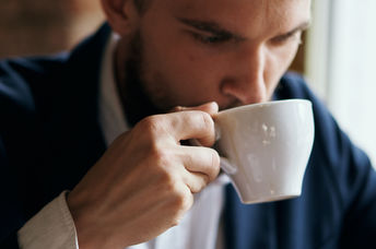 Portrait of a man enjoying a warm beverage in a porcelain cup.