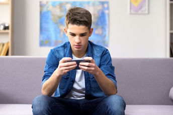 A teenager playing a game on his phone.