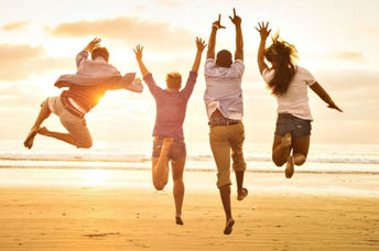 A group of friends jump for joy on the beach.