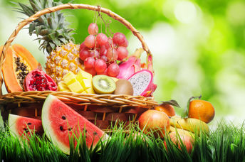 Basket of tropical fruits on green grass.