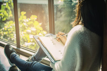 Woman writing her thoughts down in a journal.