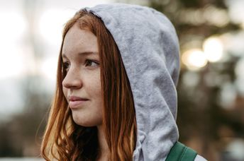 Gen Z young woman wearing a hoodie outdoors.