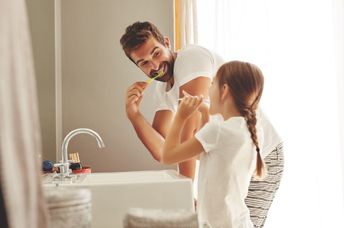 Father and daughter brushing their teeth.
