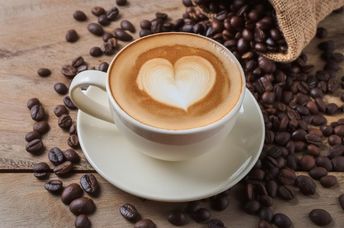 Cup of coffee latte with heart shape and coffee beans.