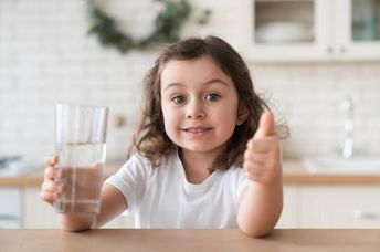 A cute girl enjoying a glass of fresh water.