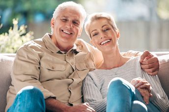 A senior couple sits on a couch.