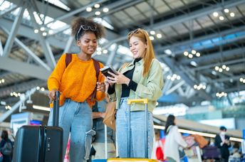 Two women stand in an airport.