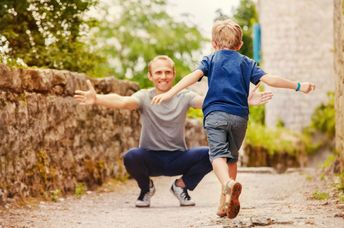 A boy runs into his father’s arms.