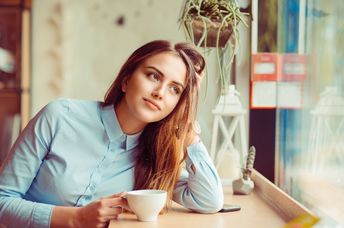 A woman daydreams while on a coffee break.