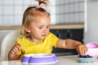 Toddler eating blueberries.