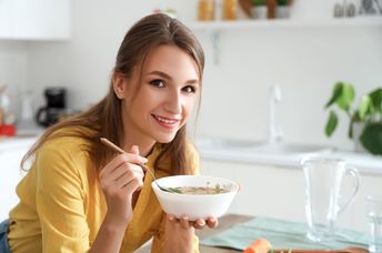 A woman eating hot chicken soup.