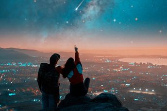 Couple watching shooting stars from a rooftop.