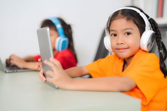 Two young students wear headphones.