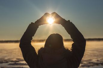 A woman makes a heart with her hands.