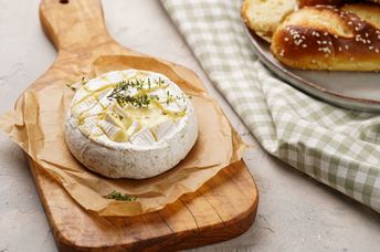 Oven baked camembert cheese on wooden board.