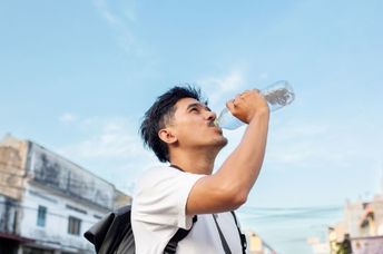 Young man drinking water from a plastic bottle.