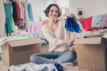 A woman holds up a pair of shoes.