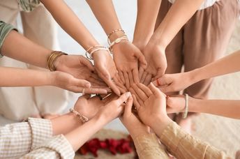 Young girls stand in a circle with their hands together.