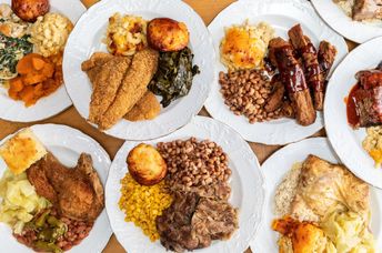 A soul food feast with a variety of dishes served on numerous plates.