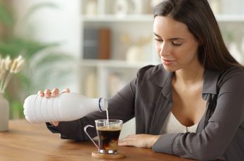 Woman adding milk to her coffee.